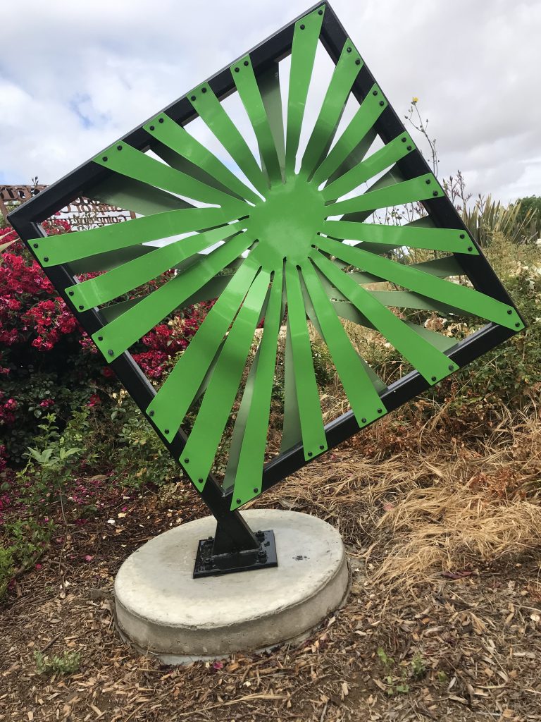 Image of bright green sunburst metal sculpture mounted on a square frame.