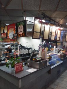 Image of restaurant counter where orders are placed is blocked by clear solid plastic.