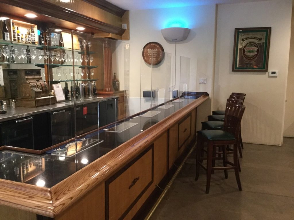 Image of a dining counter in a restaurant which has a clear plastic barrier.