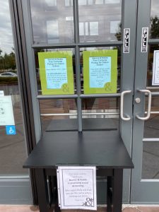 Image of small table in front of store's doors where staff place pick up orders.
