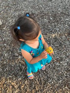 Image of child holding rock painted yellow with the word "love" on it.