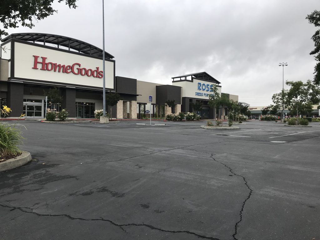Image of large, empty parking lot with HomeGoods and Ross in background.