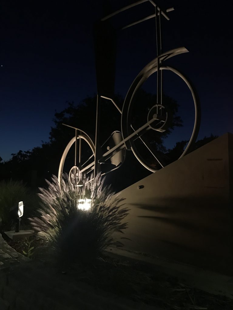 Image of large metal sculpture of stick figure on a bicycle.