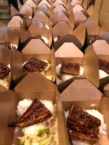 Close up image of boxed meal with white rice and piece of grilled eel.