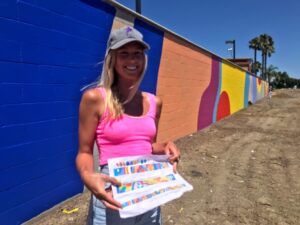 Image of woman holding rendering standing in front of wall painted colorfully.