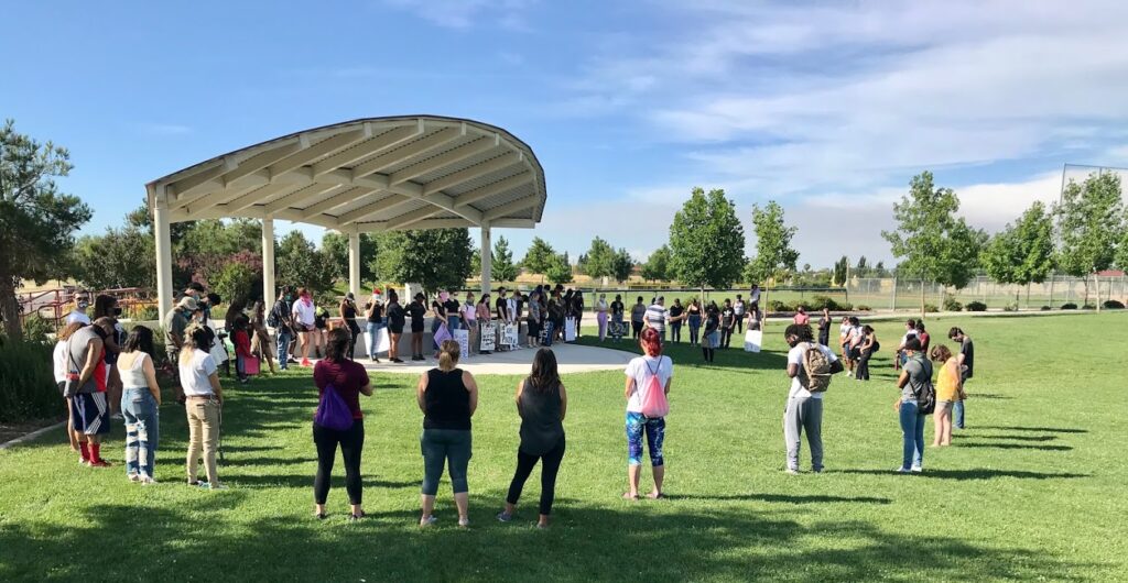 Image of about five dozen protesters standing in a large circle within an amphitheater.