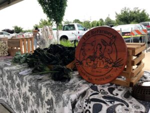 Image of ReFarmery table with produce and round wooden sign.