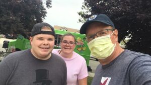 Image of three people looking into camera with food truck in background.