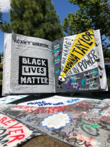 Image of large book painted with the words "Black Lives Matter" and the names of Black men and women who have died in police custody.