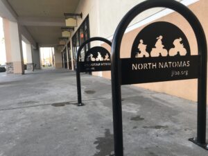 Image of metal bike rack with words North Natomas Jibe in silouette.