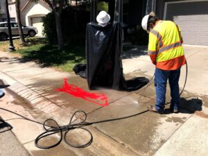 Image of man holding power washer hosing off sidewalk.