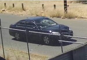 Image of dark-colored sedan with shattered windshield and dented hood.