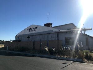 Image of old building with the words "Natomas Field" painted on the side facing the street.