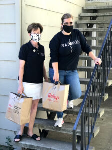 Image of Heick and Ashby standing together each holding a bag of grocers.