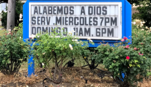 Image of sign which reads "Alabemos A Dios Serv Miercoles 7pm Domingo 8am 6pm.