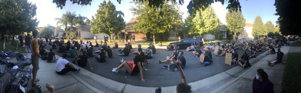 Panoramic image of protesters sitting on the road.