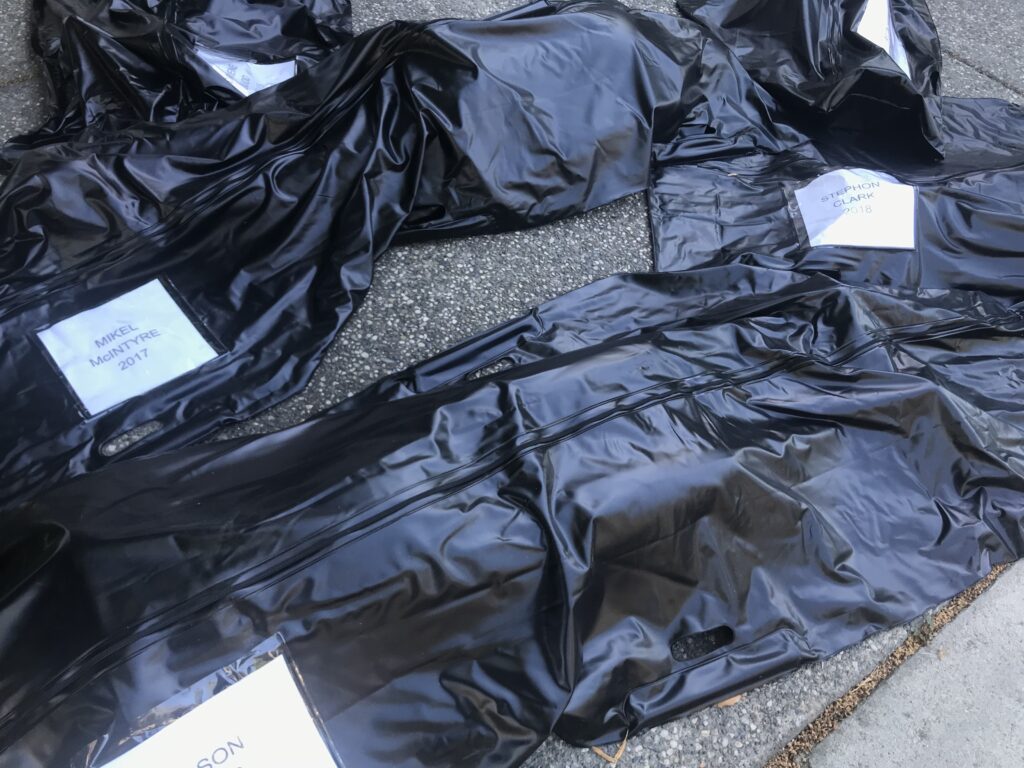 Image of several body bags with names of people who died during interactions with police.