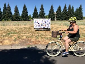 Image of woman biking past a colorful banner.
