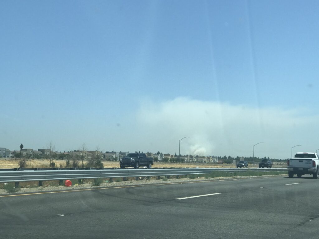 Image of freeway in foreground and plume of smoke in distance.