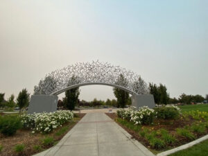 Image of an arch over a path. The arch is made of hundreds of interwoven sculpted baseball bats.