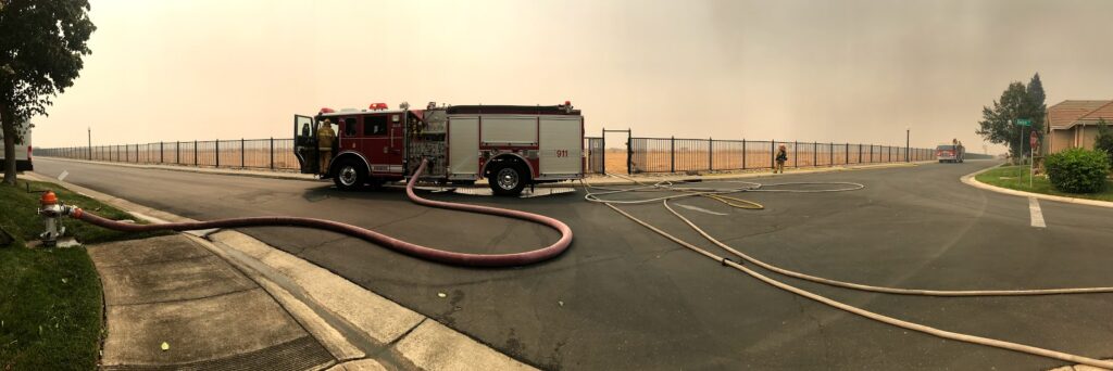 Image of fire engine and fire hose connected to nearby hydrant.