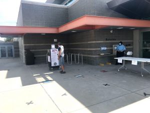 Image of man dropping ballot off at North Natomas Library while security guard looks on.