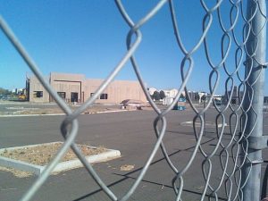 Image of unfinished building construction as seen through a chain link fence.