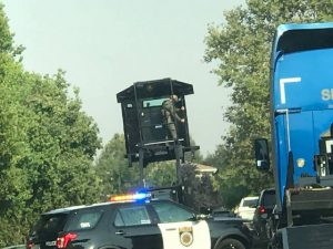 Image of SWAT officer standing on top of SacPD patrol car holding up a shield.