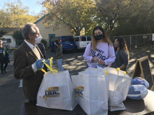 Image of city councilmember Jeff Harris speaking with one of the grocery recipients at Stanford Settlement.