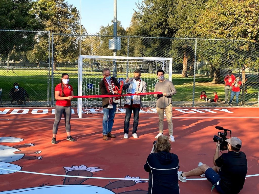 Image of man cutting red ribbon.