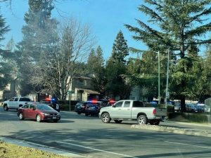 Image of several police vehicles blocking entrance to an apartment complex.