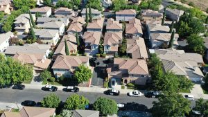 Aerial image of homes on 100 block of Dragonfly Circle. Police patrol cars and yellow police tape are visible.