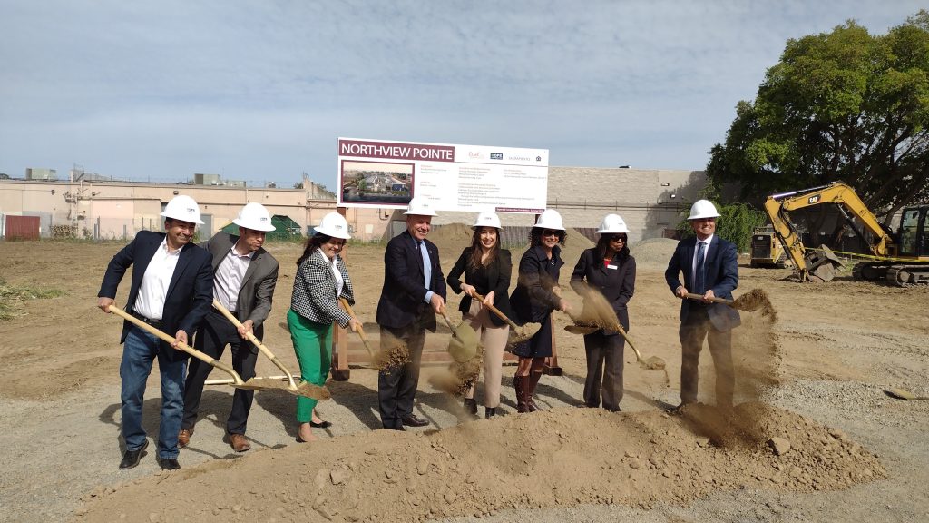 People lifting shovels of dirt at groundbreaking ceremony